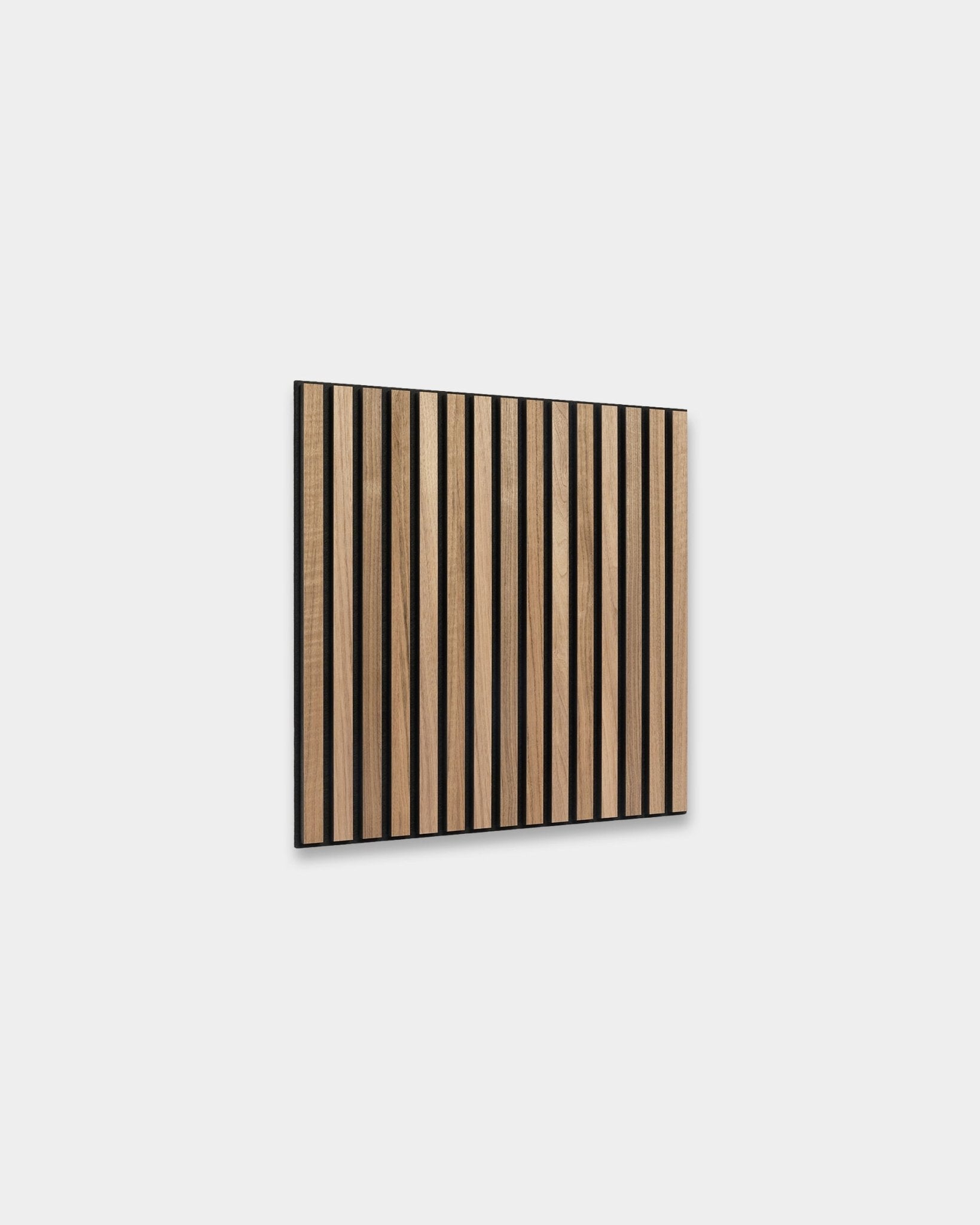 WoodUpp Akupixel Panneau acoustique en noyer, 60 x 60 cm, présente des lattes en noyer espacées de façon régulière avec des espaces black, montées sur un mur gris clair dans un style scandinave.